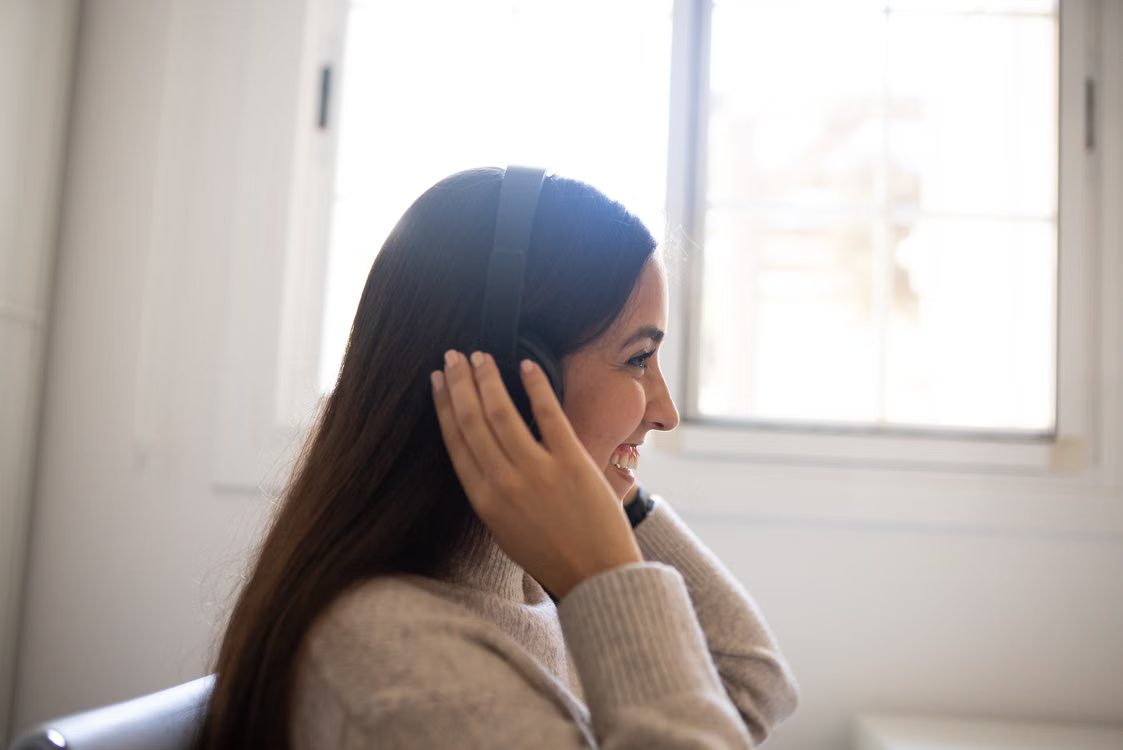 Support professional smiling while listening on a headset beside a bright window