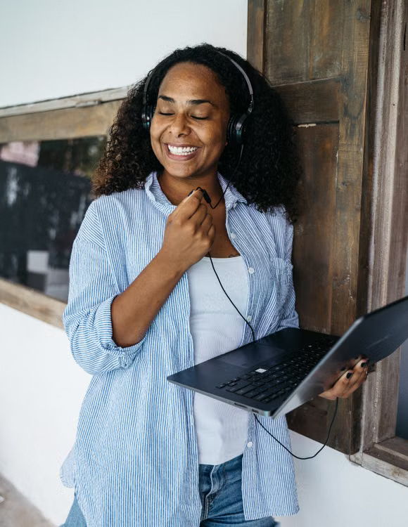 Professional holding a laptop and smiling while wearing a headset