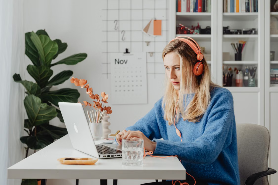 Support professional in headphones working through her schedule at a bright home office desk